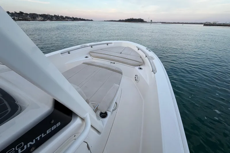 Slide: The Image of 2023 Boston Whaler 220 Dauntless boat on calm water, showcasing spacious deck and seating. - 55