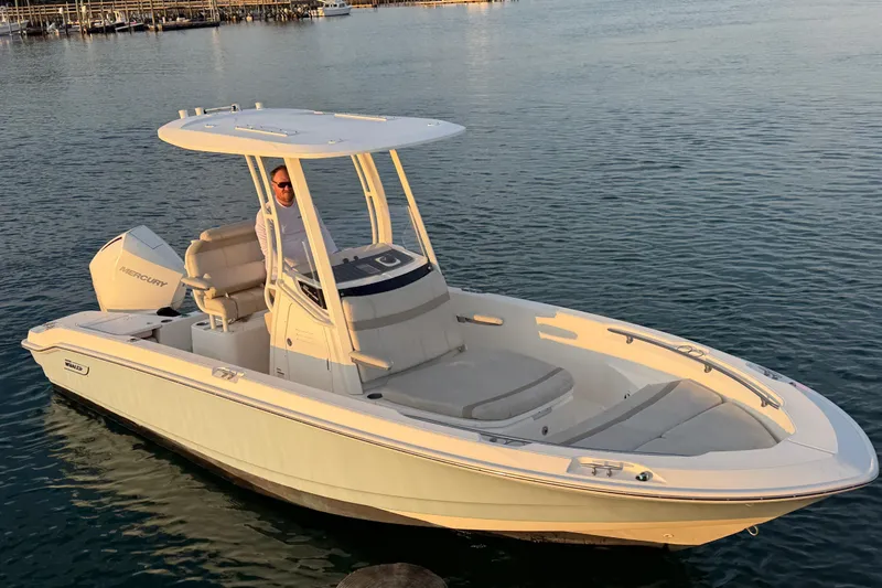 Slide: The Image of 2023 Boston Whaler 220 Dauntless boat on calm water, featuring a Mercury engine. - 6