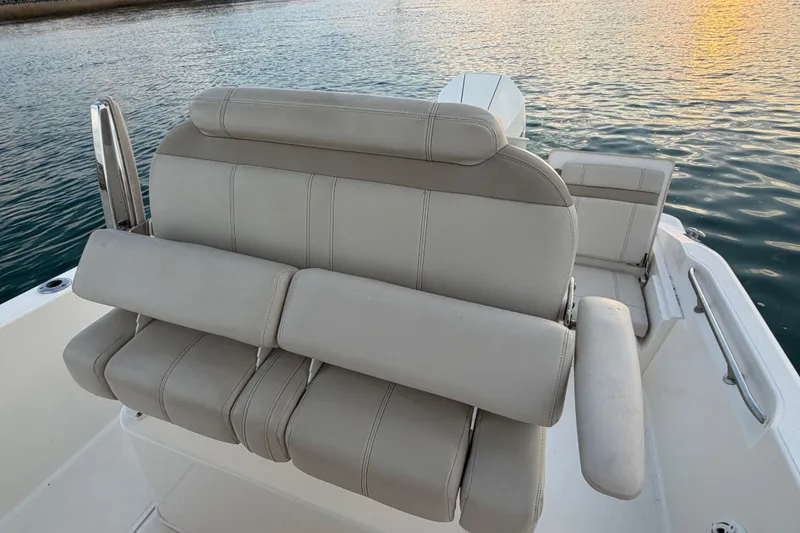 Slide: The Image of 2023 Boston Whaler 220 Dauntless boat seating, featuring comfortable beige upholstery on calm water. - 60
