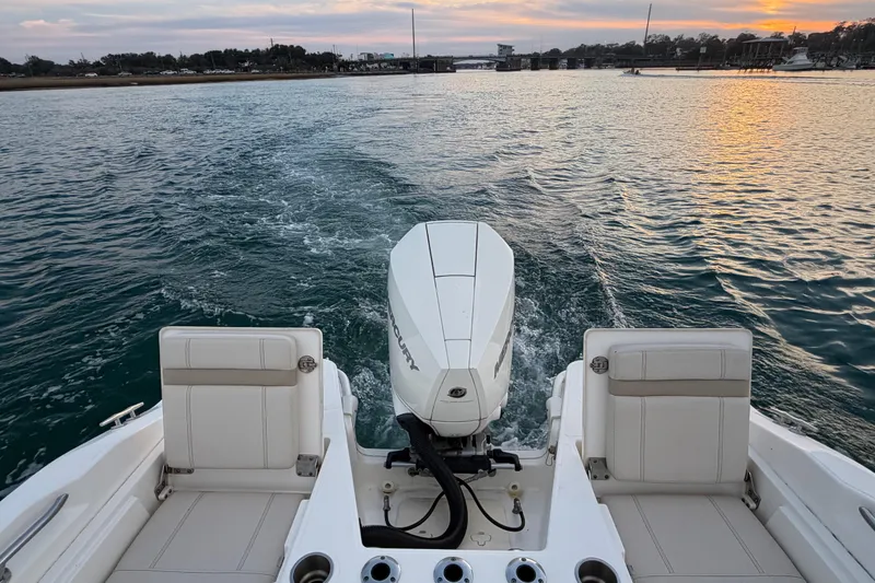 Slide: The Image of Boston Whaler 220 Dauntless 2023 cruising on water at sunset, rear view. - 63