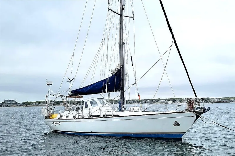 Slide: The Image of 1981 CT 49 sailboat with blue sail, anchored in calm waters. - 2