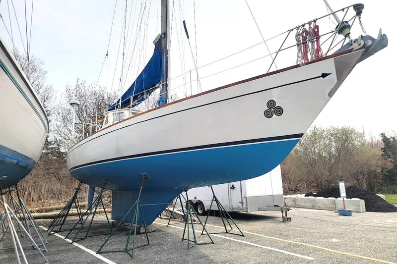 Slide: The Image of 1981 CT 47 sailboat on stands, blue hull, white deck, outdoor storage. - 3