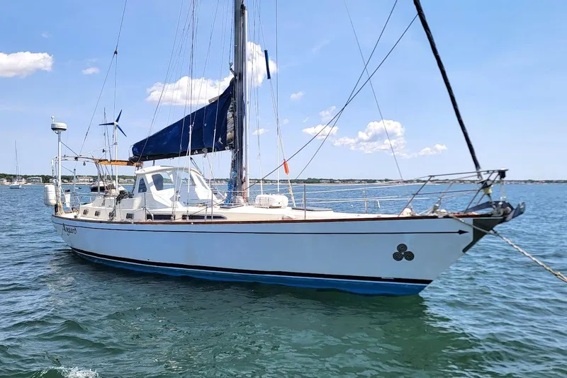 The Image of 1981 CT 47 sailboat with blue sails on calm water under a clear sky. - 0