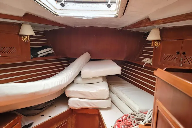 Slide: The Image of Interior of a 1981 CT 47 sailboat cabin with wooden paneling and white cushions. - 15
