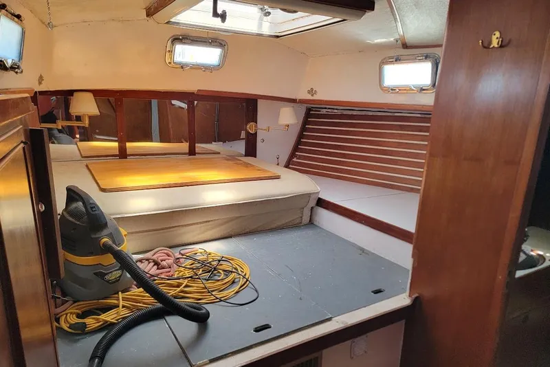 Slide: The Image of Interior of a 1981 CT 47 sailboat cabin with bed, vacuum, and wooden accents. - 21