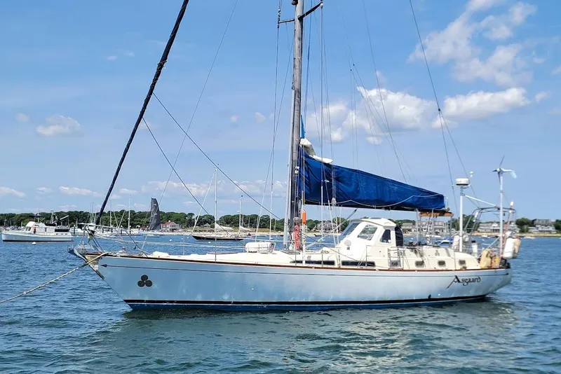 Slide: The Image of 1981 CT 47 sailboat with blue sail cover, anchored in a sunny harbor. - 29