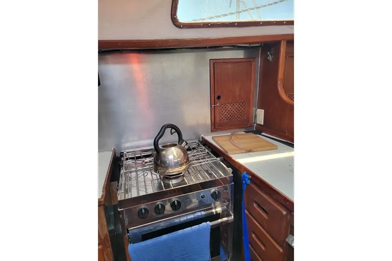 Slide: The Image of Compact kitchen area in a 1981 CT 47 boat, featuring a stove and kettle. - 34