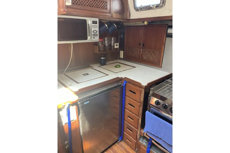 Slide: The Image of 1982 CT 47 yacht kitchen with microwave, stove, and wooden cabinetry. - 17