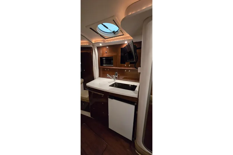 Slide: The Image of Interior of 2018 Four Winns V355 yacht featuring kitchenette with sink, microwave, and TV. - 27