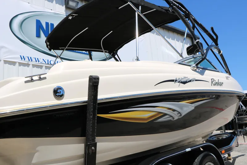 Slide: The Image of 2004 Rinker 212 Captiva Bowrider boat with black canopy and sleek design. - 10