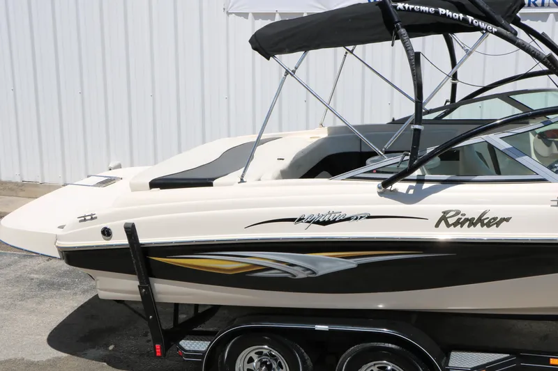 Slide: The Image of 2004 Rinker 212 Captiva Bowrider boat with sleek design and black canopy on trailer. - 21