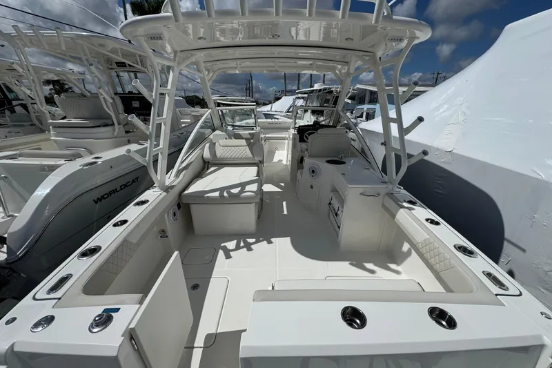 Slide: The Image of 2026 World Cat 280 DC-X boat interior with seating and fishing rod holders under a clear sky. - 6