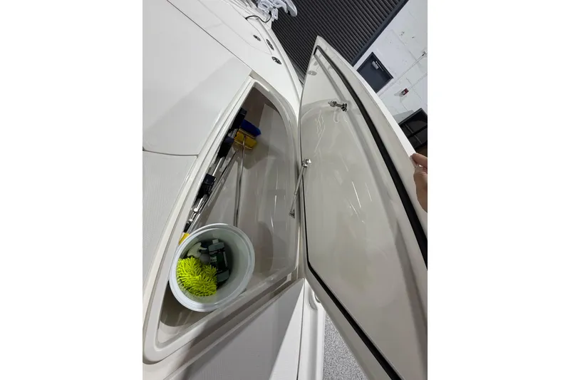 Slide: The Image of Open storage compartment on 2025 SeaVee 270Z boat, containing cleaning supplies and tools. - 45