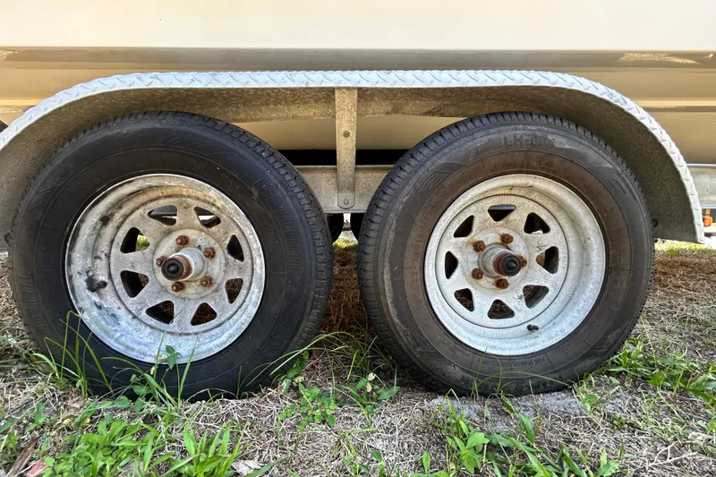 Slide: The Image of Trailer wheels of a 2020 Cobalt 23SC boat on grassy ground. - 111