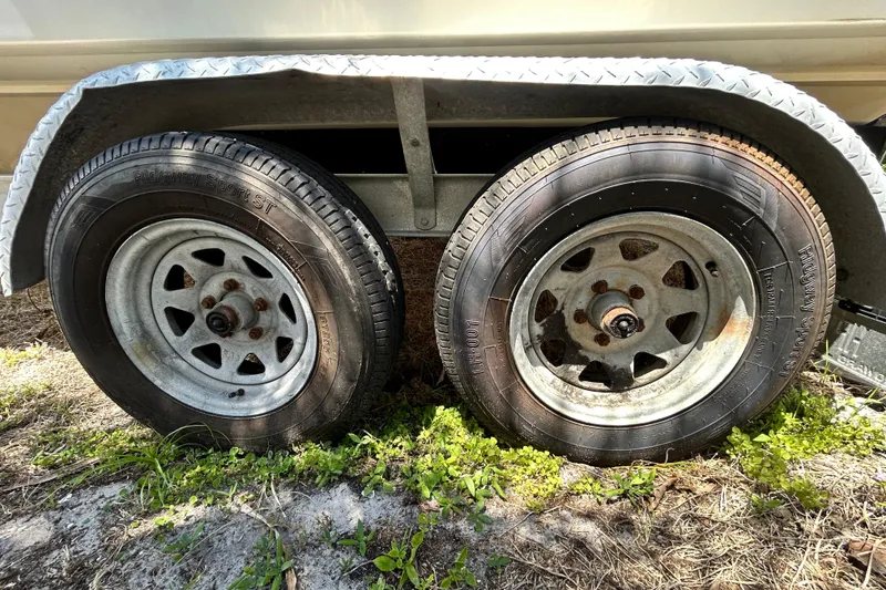 Slide: The Image of Trailer wheels of a 2020 Cobalt 23SC boat on grassy ground. - 112