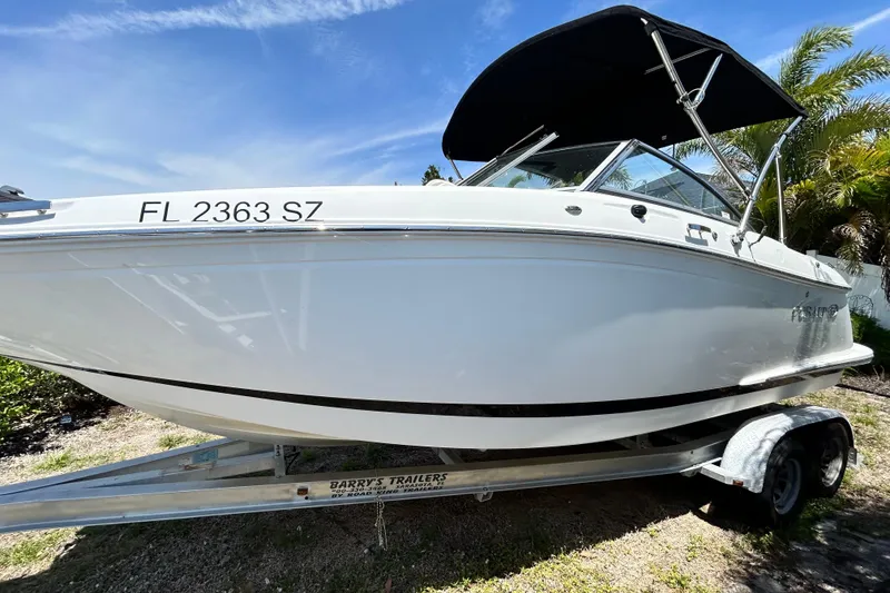 Slide: The Image of 2020 Cobalt 23SC boat on trailer, sunny day, palm trees in background. - 13