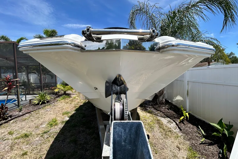 Slide: The Image of Front view of a 2020 Cobalt 23SC boat on a trailer, surrounded by tropical plants. - 16