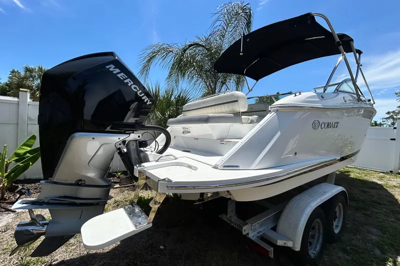 Slide: The Image of 2020 Cobalt 23SC boat with Mercury engine on trailer, under clear blue sky. - 2