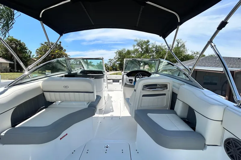 Slide: The Image of 2020 Cobalt 23SC boat interior with seating and canopy under a clear sky. - 23