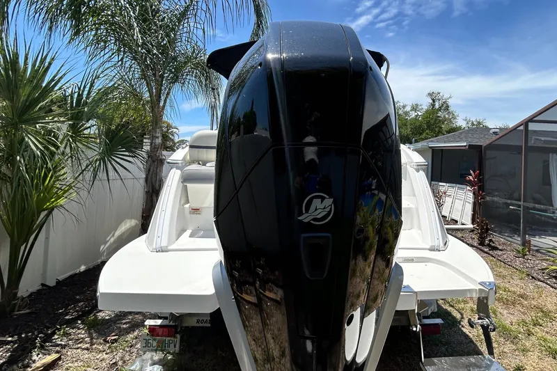 Slide: The Image of 2020 Cobalt 23SC boat with outboard motor, parked near palm trees under a clear blue sky. - 3