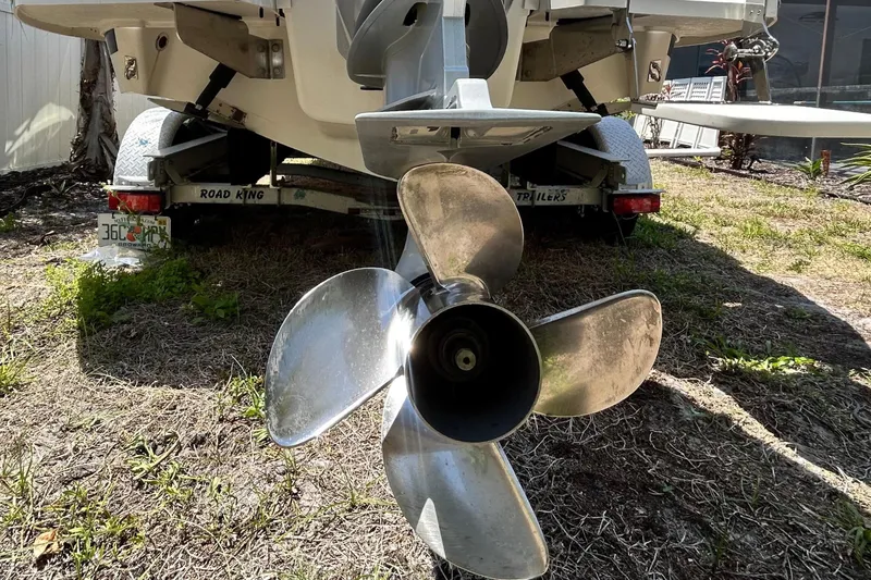 Slide: The Image of 2020 Cobalt 23SC boat rear view with propeller, parked on grass near palm trees. - 5