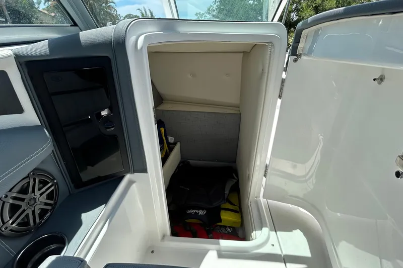 Slide: The Image of 2020 Cobalt 23SC boat interior storage compartment with open door and visible life jackets. - 52