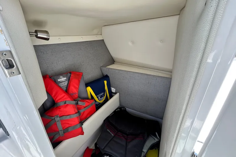 Slide: The Image of Storage compartment in a 2020 Cobalt 23SC boat with life jackets and gear. - 53