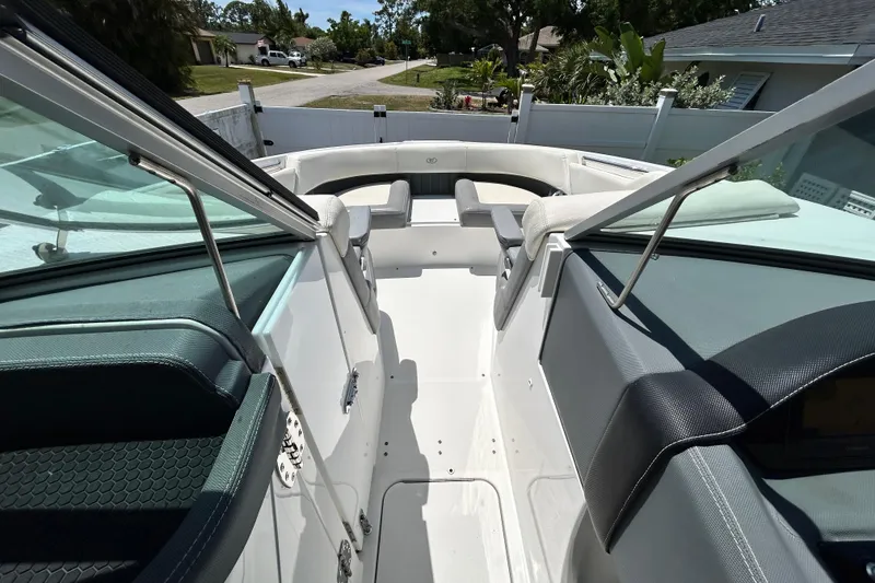 Slide: The Image of 2020 Cobalt 23SC boat interior with seating and windshield, parked in a residential area. - 59