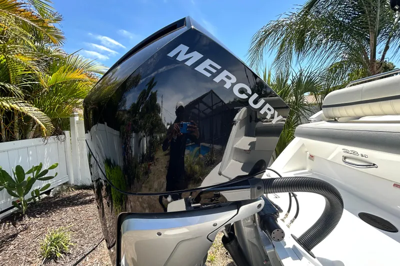 Slide: The Image of 2020 Cobalt 23SC boat with Mercury engine, surrounded by tropical plants. - 6