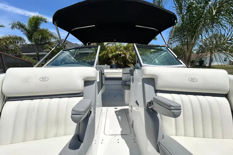 Slide: The Image of 2020 Cobalt 23SC boat interior with white seating, black canopy, and palm trees in the background. - 79