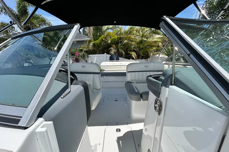 Slide: The Image of 2020 Cobalt 23SC boat interior with seating, surrounded by lush greenery. - 81