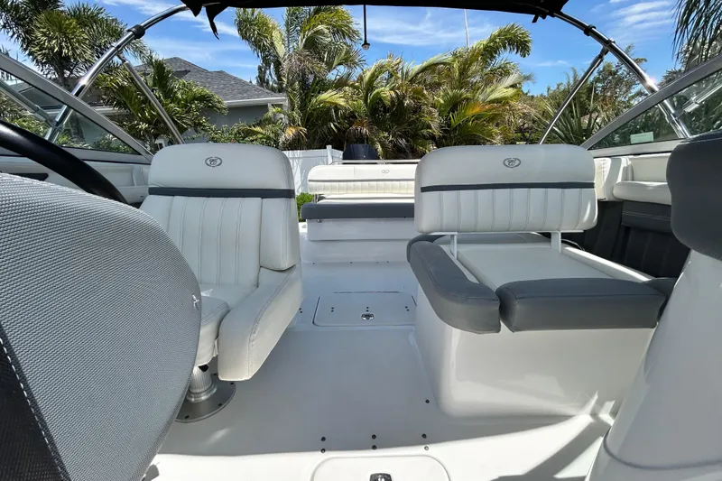 Slide: The Image of 2020 Cobalt 23SC boat interior with white seating and lush greenery background. - 83