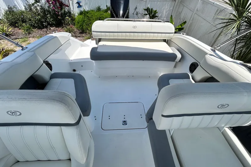 Slide: The Image of 2020 Cobalt 23SC boat interior with white and gray seating, surrounded by greenery. - 87