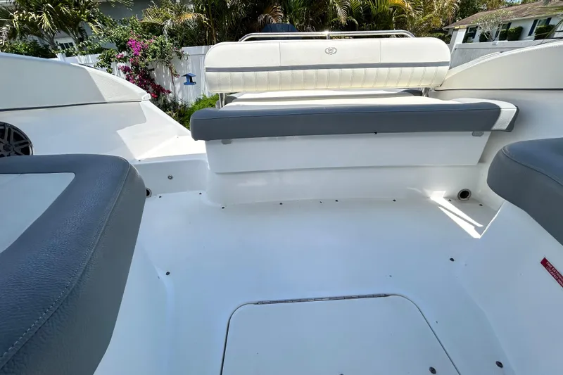 Slide: The Image of 2020 Cobalt 23SC boat interior with white and gray seating, surrounded by lush greenery. - 89
