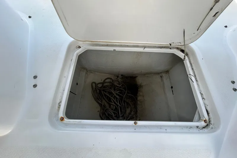 Slide: The Image of Open storage compartment on 2020 Cobalt 23SC boat with coiled rope inside. - 90