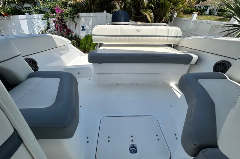 Slide: The Image of 2020 Cobalt 23SC boat interior with gray and white seating, surrounded by lush greenery. - 91