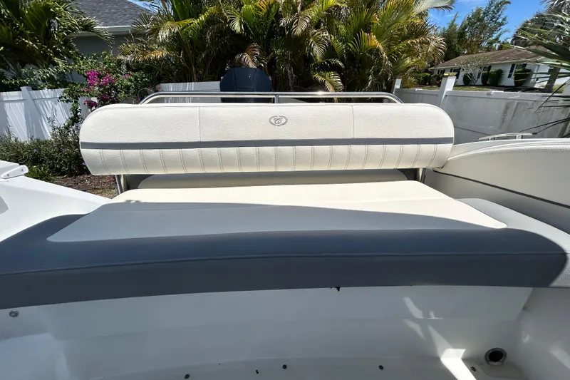 Slide: The Image of 2020 Cobalt 23SC boat interior with cushioned seating, surrounded by lush greenery. - 94