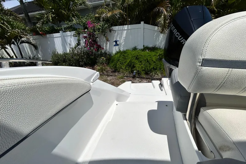 Slide: The Image of 2020 Cobalt 23SC boat interior with white seating and Mercury engine, surrounded by lush greenery. - 95