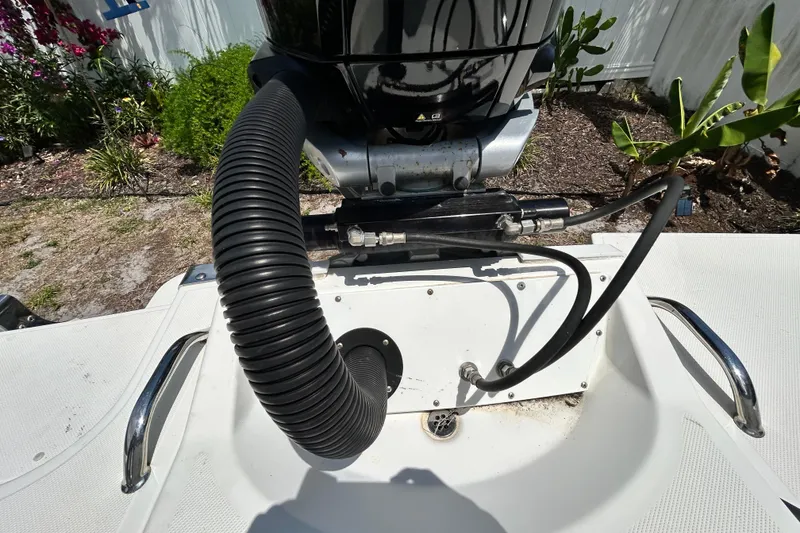 Slide: The Image of 2020 Cobalt 23SC boat engine compartment with hoses and fittings, surrounded by garden plants. - 99