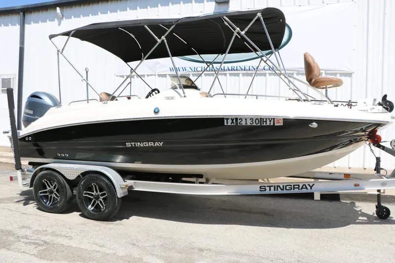 The Image of 2020 Stingray 192 SC boat on trailer, black and white design, with canopy. - 1