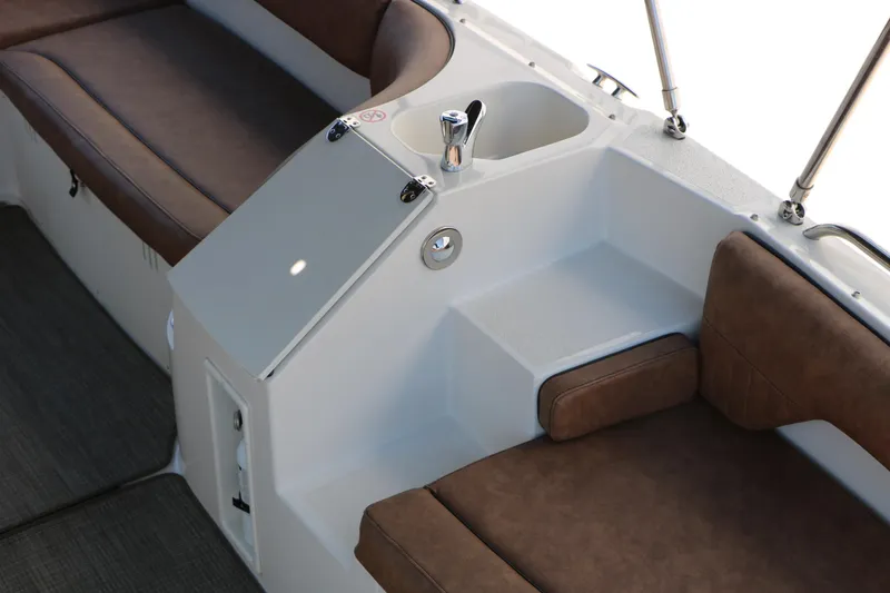 Slide: The Image of 2020 Stingray 192 SC boat interior with brown seating and built-in sink. - 23