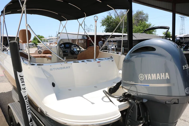 Slide: The Image of 2020 Stingray 192 SC boat with Yamaha 150 engine, docked under a canopy. - 7