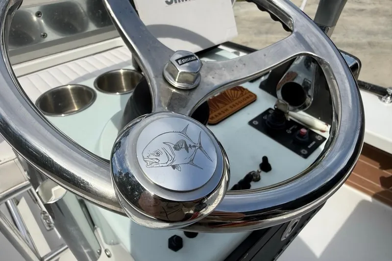 Slide: The Image of Steering wheel of 2017 East Cape Vantage boat with fish emblem and controls. - 19