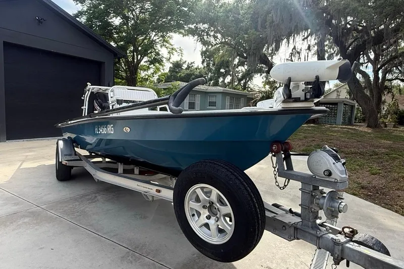 Slide: The Image of 2017 East Cape Vantage boat on trailer in driveway, surrounded by trees and houses. - 2