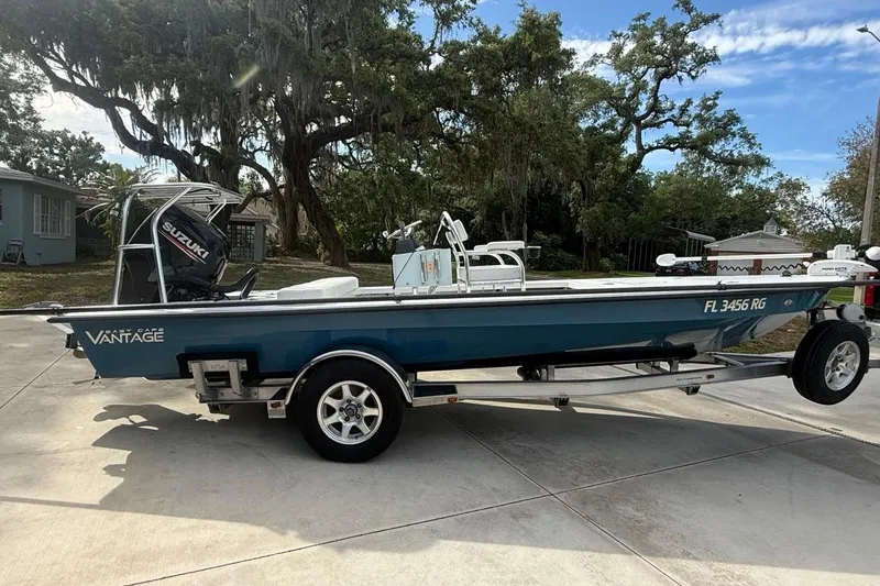 Slide: The Image of 2017 East Cape Vantage boat on trailer, parked in driveway under trees. - 8