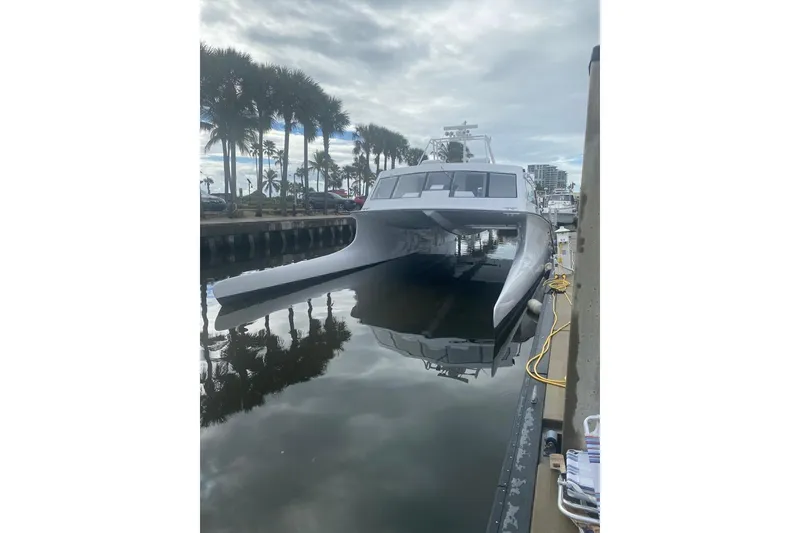 Slide: The Image of Gold Coast fast ferry, 2003 model, docked by palm trees under cloudy skies. - 2