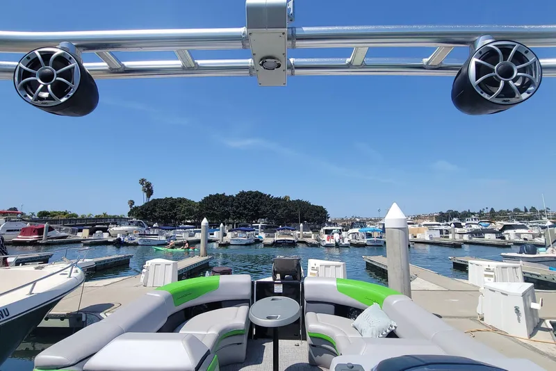 Slide: The Image of 2023 South Bay 525UL AR pontoon boat docked at a marina under clear blue skies. - 17