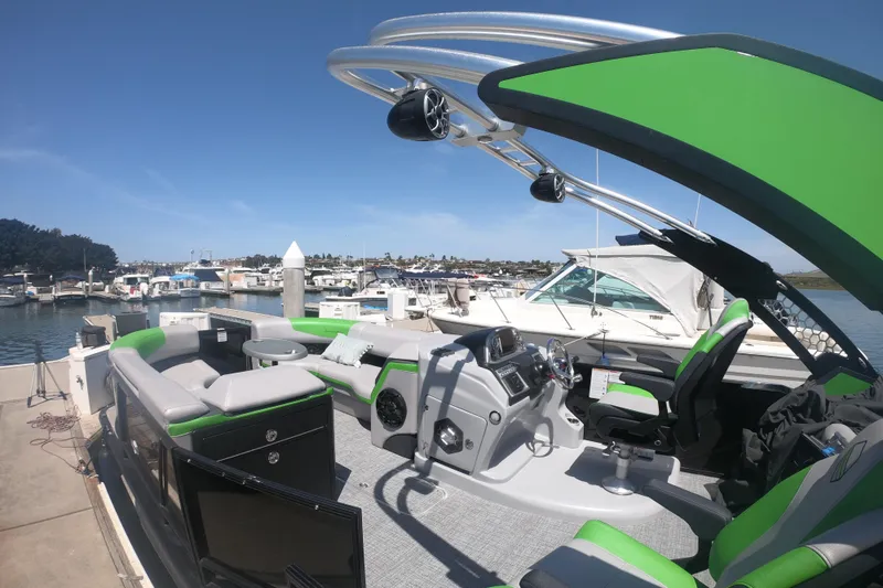 Slide: The Image of 2023 South Bay 525UL AR pontoon boat with green accents docked at a marina. - 6