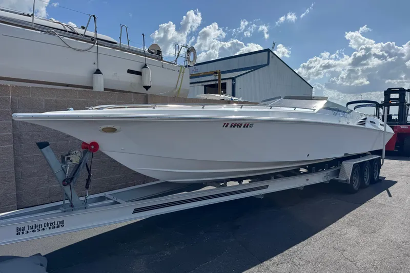 The Image of 2004 Fountain 35 Executioner speedboat on trailer, parked outdoors under a partly cloudy sky. - 0