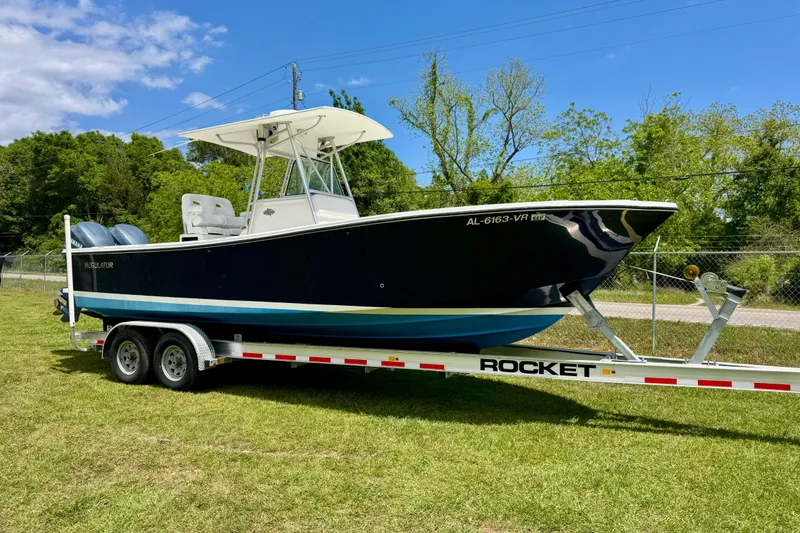 The Image of 2000 Regulator 26 Forward Seating boat on trailer, parked on grass under blue sky. - 1